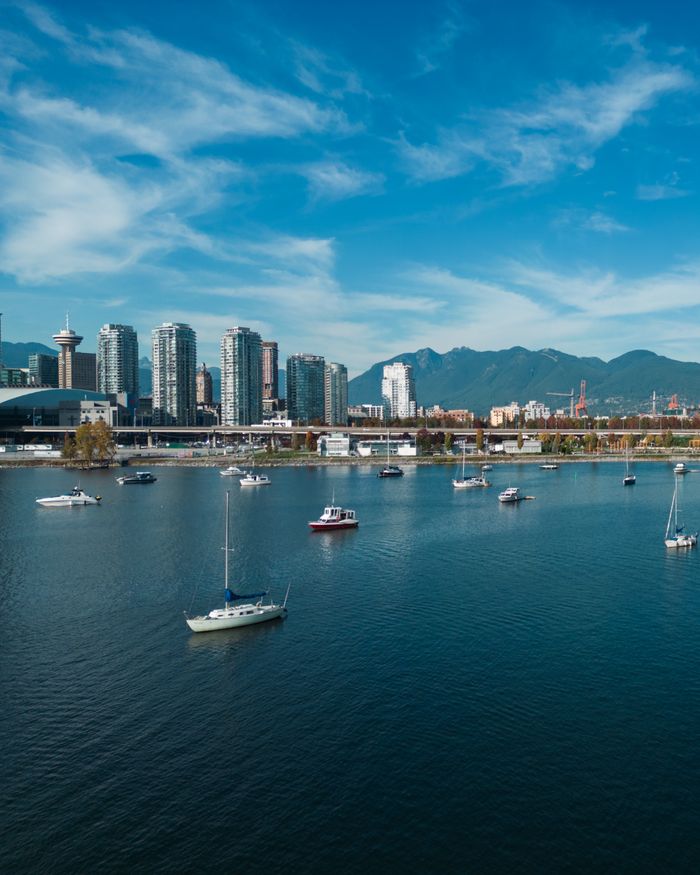 A stunning aerial view of Vancouver Harbor featuring sailboats against a backdrop of the city's skyline and mountains.