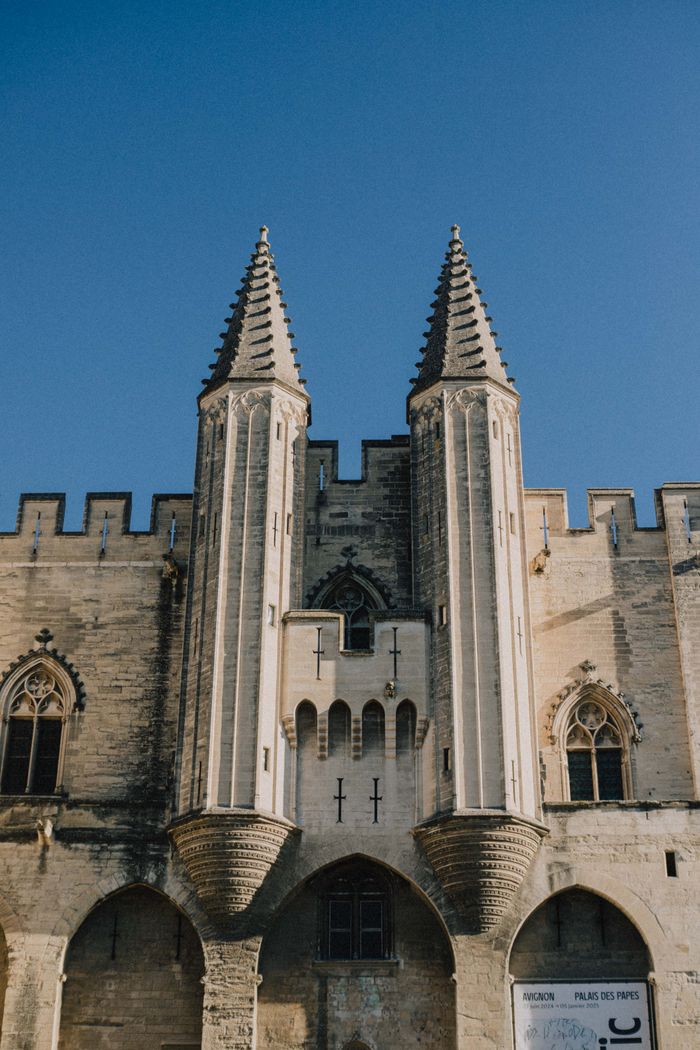 Majestic towers of Palais des Papes in Avignon, France against a clear blue sky.