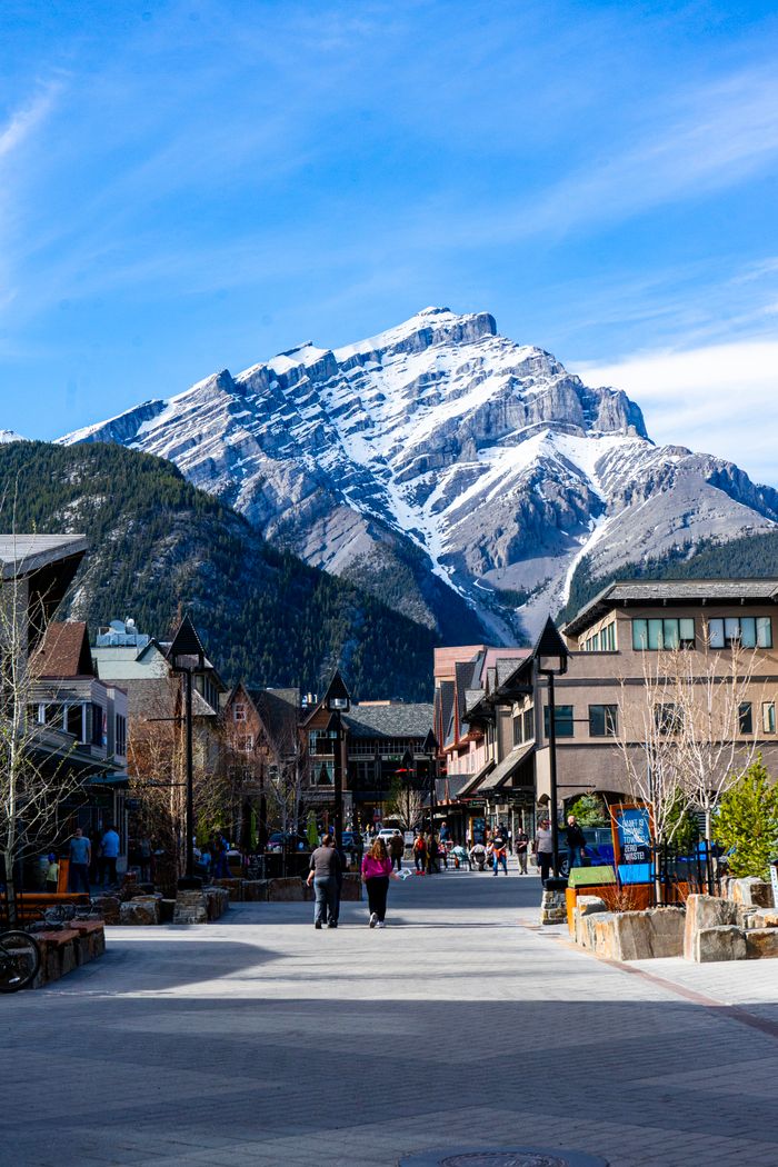 Stunning view of Banff town with snow-capped mountains in the background on a sunny day.